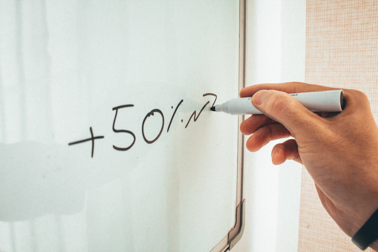 About Crop anonymous male teacher writing math formulas on whiteboard during lessons in modern classroom