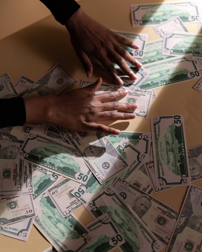 Services A close-up shot of hands spreading various US dollar bills on a table, highlighting financial abundance.