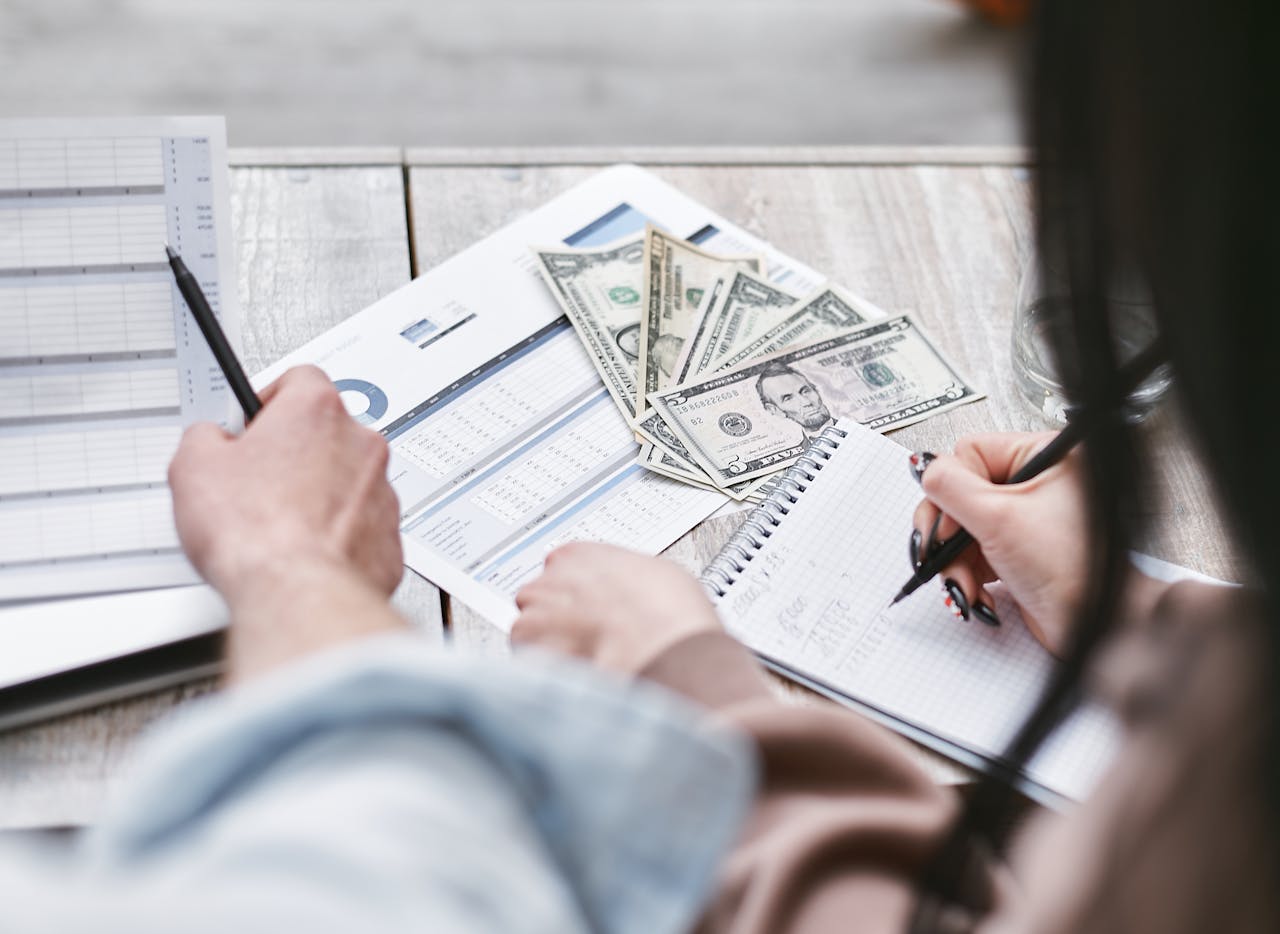 Home Two people working on financial documents and dollar bills for budgeting.